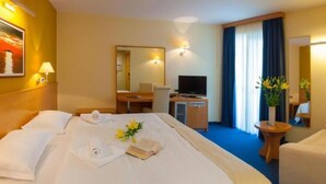 A hotel room with a large bed, a desk with a television, a chair, and a small table with flowers. - Premium Double Room With Private Bathroom 2 (Gradac)