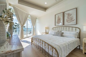 Una camera da letto con un letto grande, un comodino, una lampada e due stampe botaniche incorniciate appese al muro.