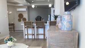 Een moderne woonkamer met een ronde houten salontafel, een witte marmeren tafel en een rustieke open haard.