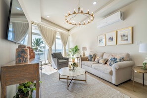 Ein modernes Wohnzimmer mit einer Couch, Sesseln, einem Couchtisch und einer Deckenleuchte.