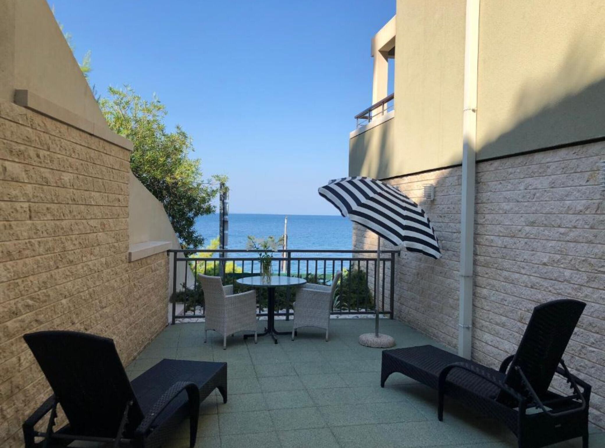 A balcony with a view of the sea, furnished with chairs and a table.