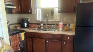 A kitchen with wooden cabinets, a stainless steel refrigerator, a sink, and a window with blinds. - Welcoming 1-bedroom apartment with AC in charming Jackson (Jackson)