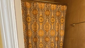 A bathroom with a patterned shower curtain, a toilet, and a bathtub. - Welcoming 1-bedroom apartment with AC in charming Jackson (Jackson)