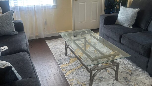A living room with a glass coffee table, two sofas, a patterned rug, and a door. - Welcoming 1-bedroom apartment with AC in charming Jackson (Jackson)