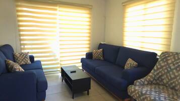 A living room with two blue sofas, a patterned armchair, and a small black coffee table.