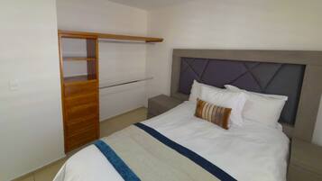 A hotel room with a bed, a wooden wardrobe, and a nightstand.