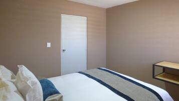 Une chambre à coucher avec un lit, une porte et une petite étagère.