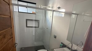 Un bagno moderno con doccia vetrata, un water bianco, un lavandino con specchio e un tappeto decorato.