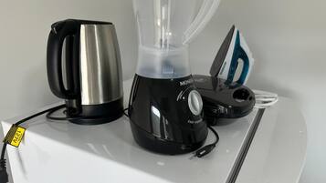 A kitchen with a blender, kettle, and iron on a white countertop.
