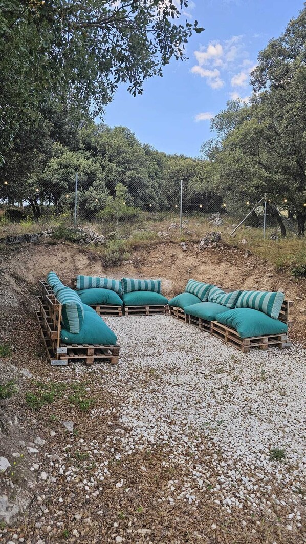 Een terras met houten zitplaatsen en groene kussens.