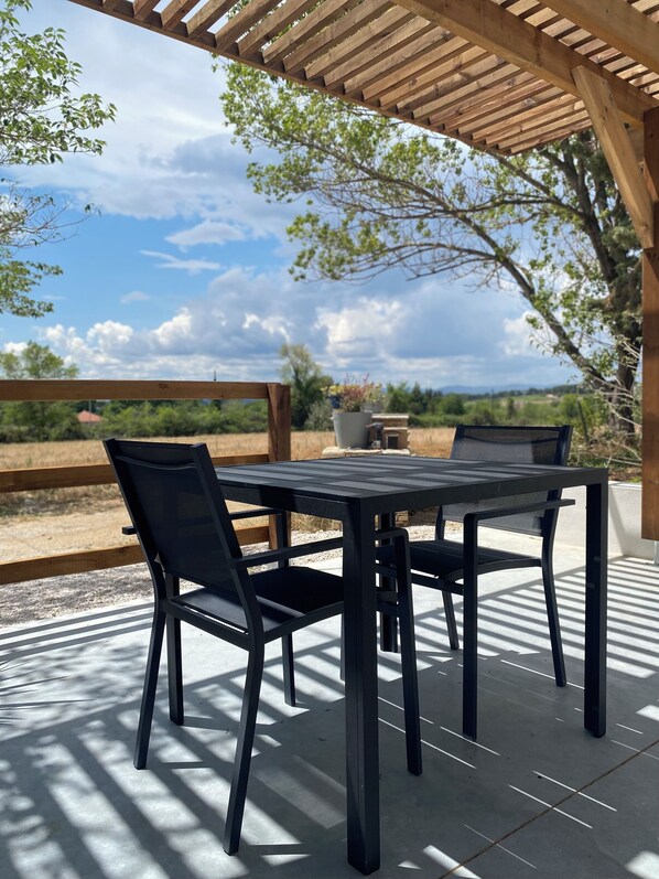 Un patio al aire libre con una pérgola de madera, una mesa y sillas.