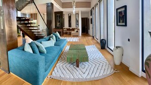 A modern living room with a blue sofa, a patterned ottoman, and a large vase. - Villa Octagon-with private pool&Heated Jacuzzi-13 min from center Essaouira  (Essaouira)