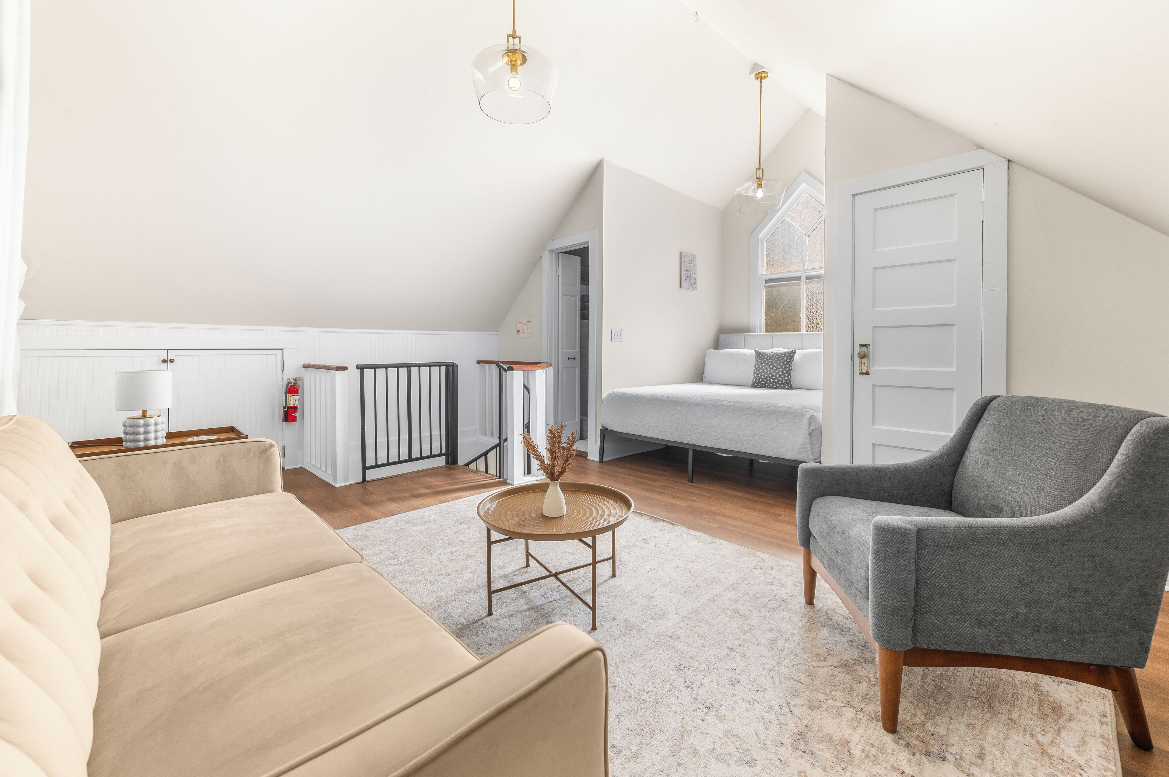 Ett modernt vardagsrum med en beige soffa, en grå fåtölj och ett litet soffbord i trä.
