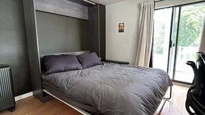 Moderni huone, jossa on sänky, patteri, ikkuna verhoilla ja tuoli.