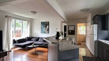 Un espacio de estar moderno con cocina, comedor y zona de estar con sofá y mesa de centro.