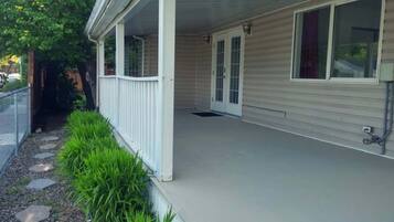 Una casa con porche cubierto, patio cercado y un camino que lleva a la entrada.
