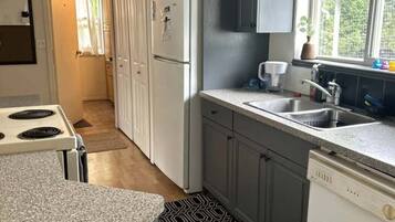 Cocina pequeña con refrigerador, estufa y lavabo.