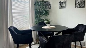 Ruokailutila, jossa on pyöreä pöytä, mustat tuolit ja ruukussa oleva kasvi.