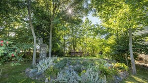 A garden with a stone structure, wooden chairs, and a variety of plants. - Your private retreat in the heart of Bohemia, in the middle of the natural paradise of Křivoklátsko (Velká Buková)