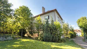 A two-story house with a garden, a visible chimney, and a paved driveway. - Your private retreat in the heart of Bohemia, in the middle of the natural paradise of Křivoklátsko (Velká Buková)