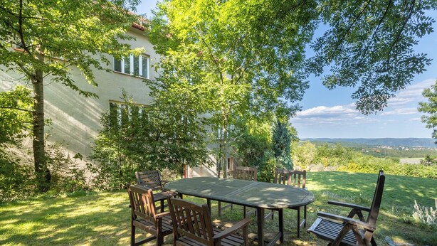 An outdoor patio with a table and chairs, surrounded by trees and a view of a distant landscape. - Your private retreat in the heart of Bohemia, in the middle of the natural paradise of Křivoklátsko (Velká Buková)