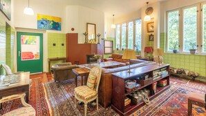 A cozy room with a large wooden desk, a sofa, and a patterned rug. There are two windows with plants on the windowsill. - Your private retreat in the heart of Bohemia, in the middle of the natural paradise of Křivoklátsko (Velká Buková)