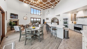 A spacious kitchen with a large island, modern appliances, and a high ceiling with wooden beams.