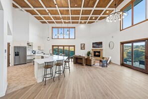 Una cocina amplia con una isla grande, piso de madera y un techo alto con vigas a la vista.