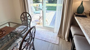 Ein Zimmer mit Glastür zu einer Terrasse, einem Tisch mit Stühlen, einer Lampe und einem Sofa.
