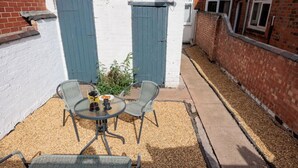 A small patio with a round table and two chairs, surrounded by gravel. - Charming Central Leicester 4 Bed Accommodation (Leicester)