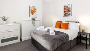 A hotel room with a bed, a dresser, and two framed pictures on the wall. - Charming Central Leicester 4 Bed Accommodation (Leicester)