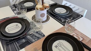 Een eettafel gedekt met zwart-witte borden, bestek en een middelpunt.