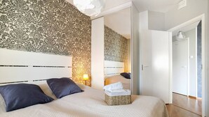 Ein Schlafzimmer mit einem großen Bett, zwei Kissen, einer Nachttischlampe und einem Korbwäscheschrank.