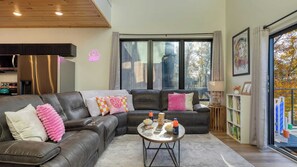 Ein modernes Wohnzimmer mit einem Ecksofa, einem Couchtisch und Blick ins Freie.
