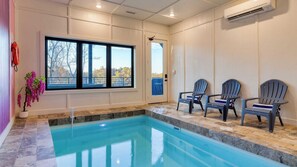 Ein Pool mit Blick auf Bäume, drei Adirondack-Stühle und eine Klimaanlage an der Wand.