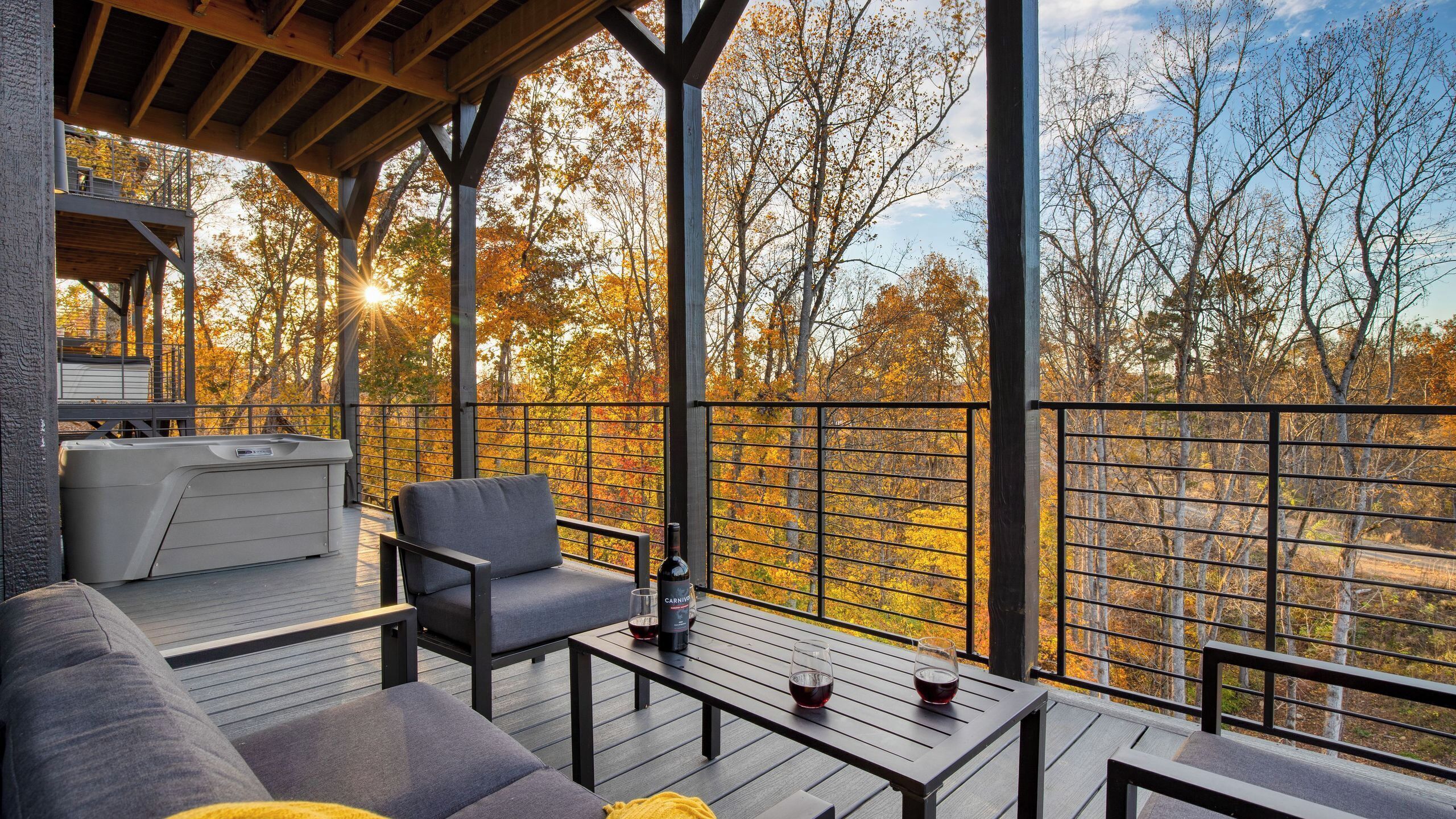 An outdoor deck with seating, a grill, and a view of autumn trees.