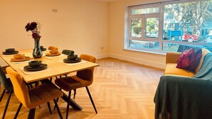 A dining area with a wooden table, chairs, and a vase of flowers. - Beautiful 2 bedroom apartment in fantastic central location close to High Street (Sutton)