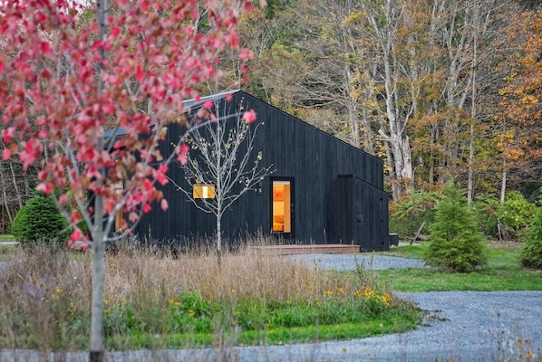 A modern black building with a visible entrance and a small porch area. - Loft 3 - Designer Cabin, Walls of Light, Sauna (West Windsor)