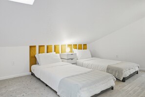 A bedroom with two beds, a bedside table, and a wall-mounted light fixture. - Loft 3 - Designer Cabin, Walls of Light, Sauna (West Windsor)