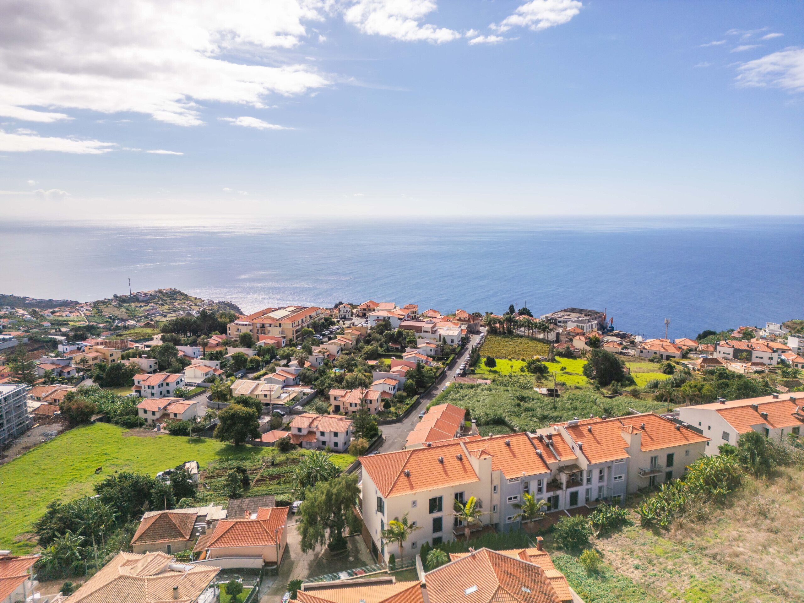 Una zona residencial costera con casas, vistas despejadas al mar y un paisaje montañoso.