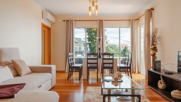 A modern living room with a sofa, dining table, chairs, and a TV. - Freitas House by Homie (Ponta do Sol)