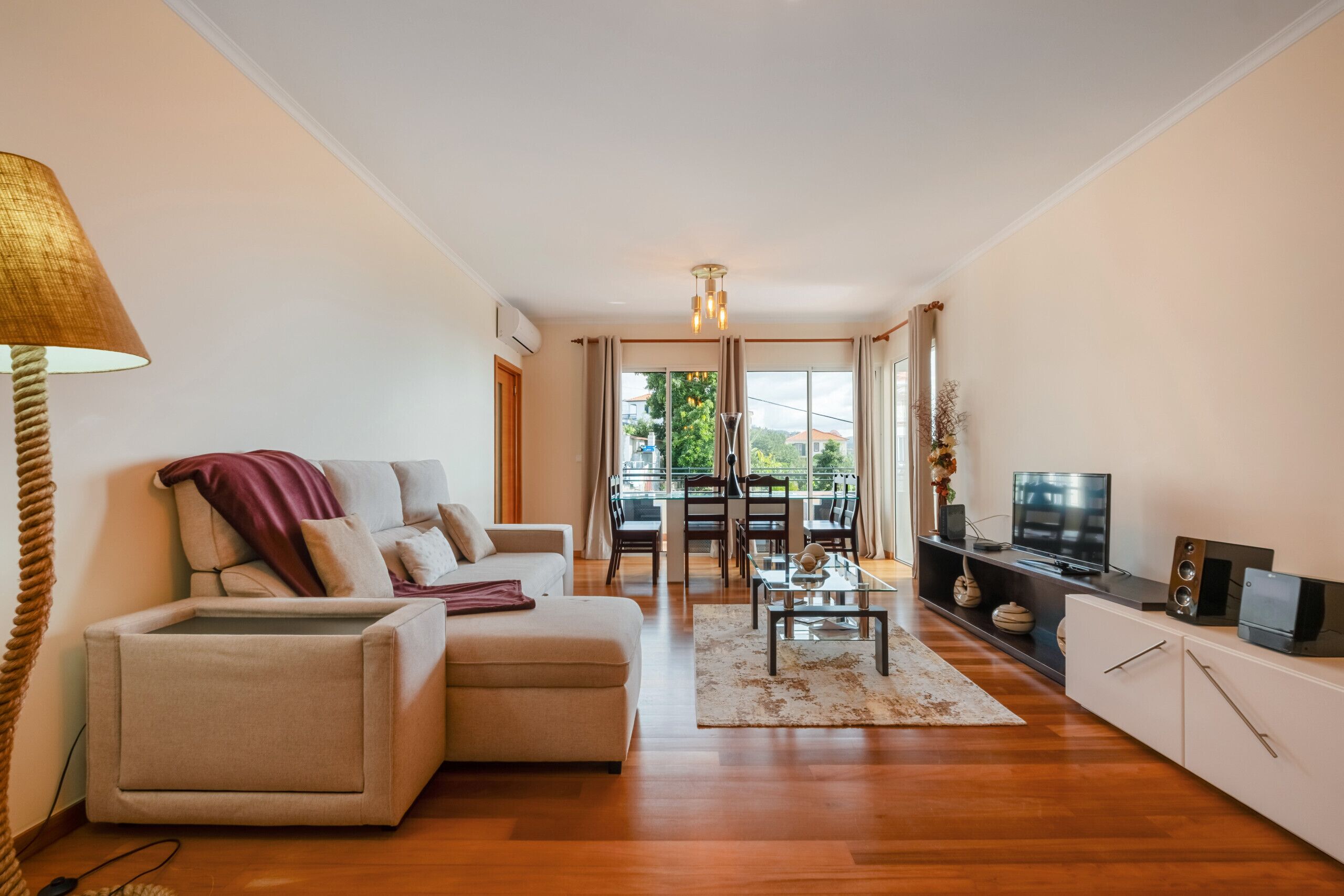 A modern living room with a sofa, TV, and a dining area with a glass table.