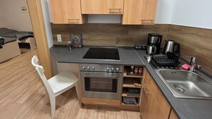 Une cuisine compacte avec des meubles en bois, un four encastré, une machine à café et un évier.