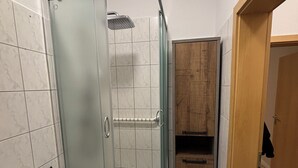 Une salle de bain avec une douche en verre, un lavabo et des meubles en bois.
