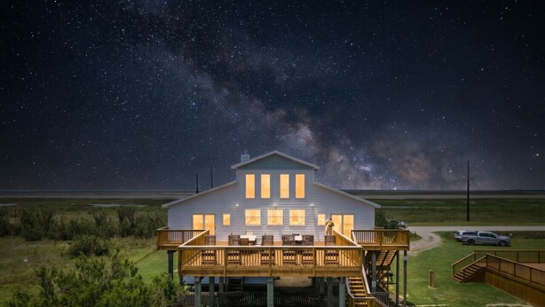A house with a deck, a garage, and a car parked nearby. - Private Beachfront Home with Ocean Views & Pool (Surfside)