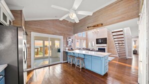 A spacious kitchen with a central island, wooden flooring, and a ceiling fan. - Private Beachfront Home with Ocean Views & Pool (Surfside)
