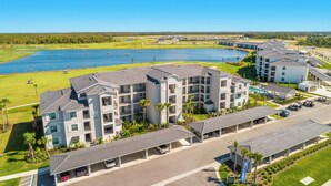 A multi-story hotel with a parking area and a view of a lake. - Top-Floor Babcock Ranch Condo Near Fort Myers • Pool, Golf, SW Florida (Punta Gorda)