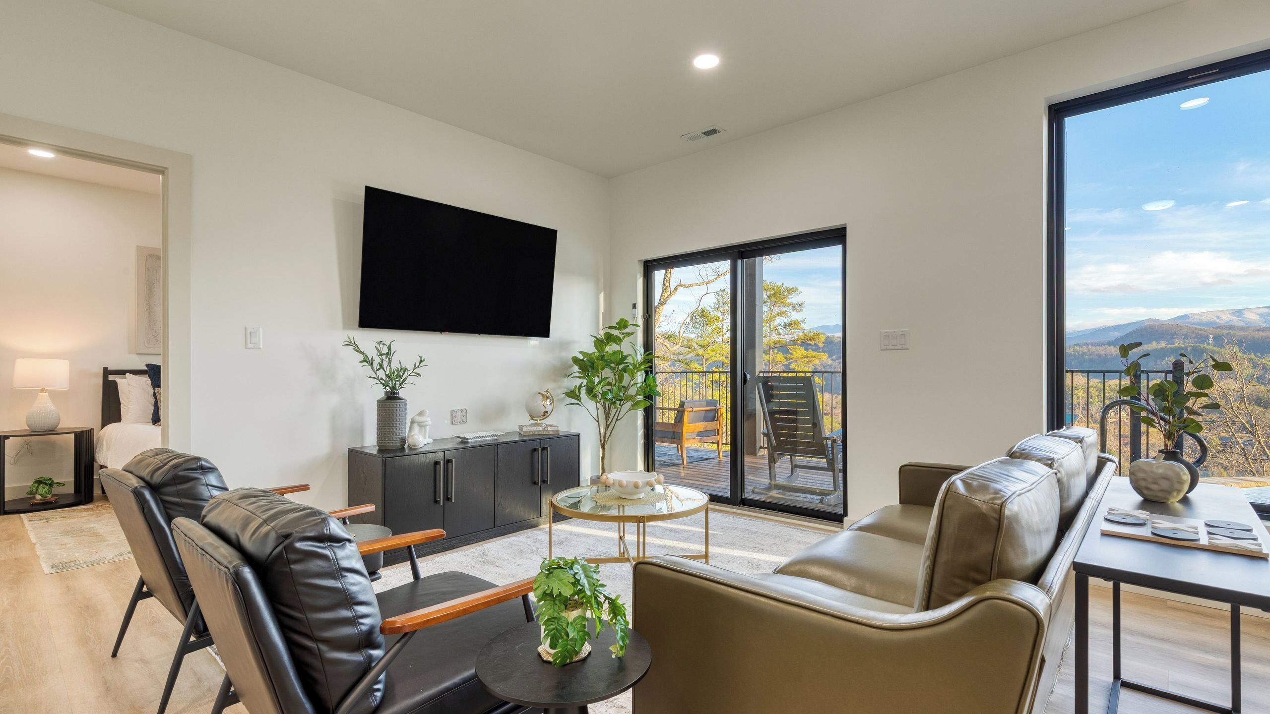 A modern living room with a sofa, chairs, a coffee table, and a TV mounted on the wall.