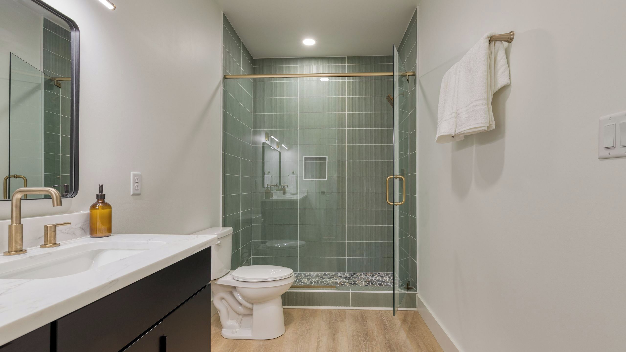 A bathroom with a glass-enclosed shower, a white toilet, and a vanity with a marble countertop.