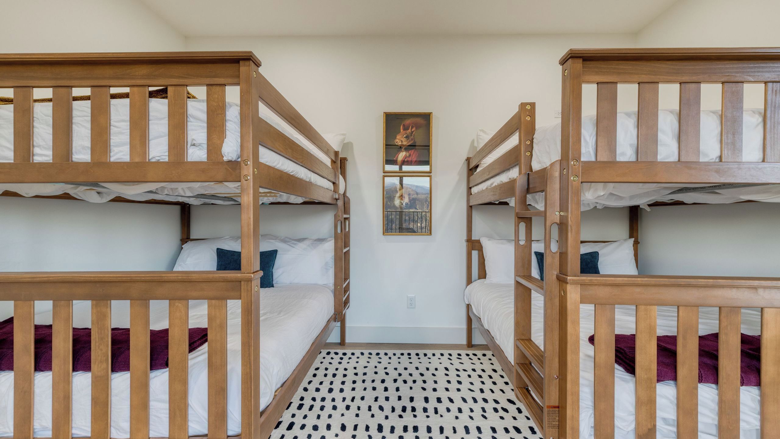 A room with bunk beds, a patterned rug, and a framed picture on the wall.
